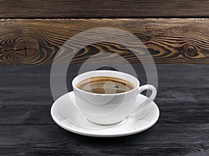 Overhead view of a freshly brewed mug of espresso coffee on rustic wooden background with woodgrain texture. Coffee break style