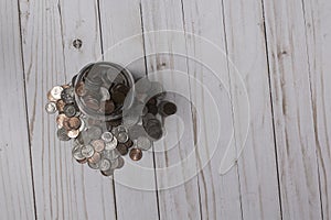 Overhead view of a glass  mason jar full of coins on a wood slat surface