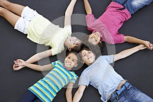 Overhead View Of Group Of Children Lying On Trampoline Together