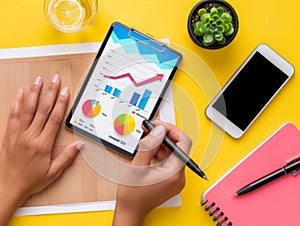 Overhead view of hands reviewing colorful growth charts on a digital tablet