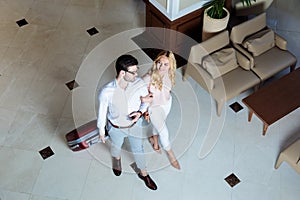 overhead view of happy couple of travelers walking with luggage