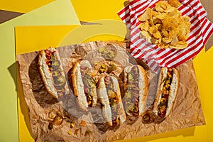 Overhead view of hots dogs served with potato chips served on papers photo