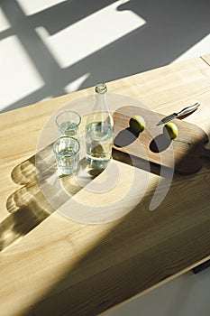 overhead view of limes on wooden board and water in glasses and bottle