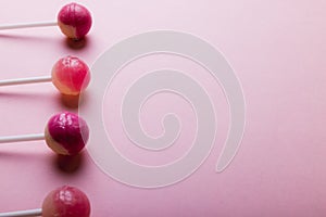 Overhead view of lollipops arranged side by side with copy space against pink background photo