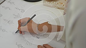 Overhead view looking down jewelry designer in studio sketching out designs