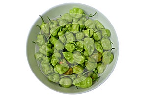 Overhead view of lots of green Capsicum Chinense chili pepper pods in large ceramic bowl