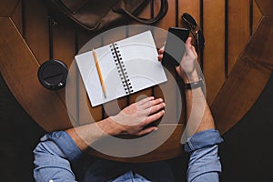 overhead view of man with opened notepad using smartphone