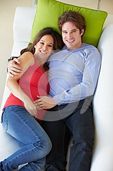 Overhead View Of Man Relaxing On Sofa With Pregnant Wife