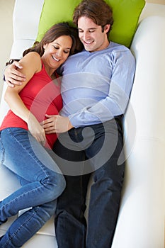 Overhead View Of Man Relaxing On Sofa With Pregnant Wife