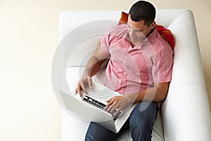 Overhead View Of Man Relaxing On Sofa Using Laptop