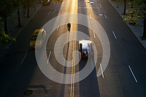 Overhead view of man riding a bike through streets of New York City with the light of sunset in the background casting long
