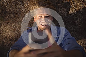 Overhead view of man smart phone while lying on field