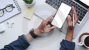 Top view man using smart phone at white office desk.