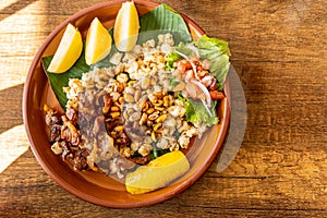 Overhead view of mote con chicharrÃÂ³n, corn with pork skin in an earthenware bowl with potatoes and toast. Traditional dish from photo