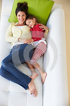 Overhead View Of Mother And Daughter Relaxing On Sofa