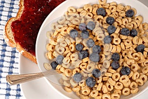 Overhead view of oat cereal with blueberries and spoon, toast wi