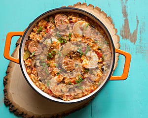 Overhead view of an orange enamel cast iron pot filled with Cajun etouffee on a turquoise table.