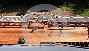 Overhead view of outdoor cedar wooden deck being remodeled with power and hand tools on floor boards