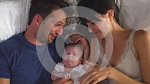 Overhead View Of Parents Lying In Bed Cuddling Baby