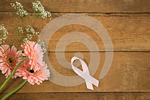 Overhead view of pink Breast Cancer Awareness ribbon by gerbera flowers