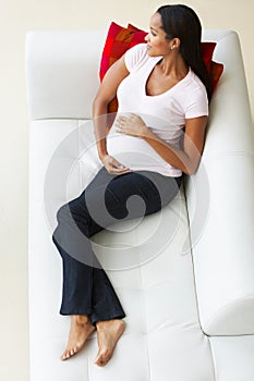 Overhead View Of Pregnant Woman Relaxing On Sofa