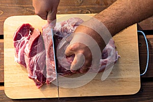 Overhead view of raw piece of pork on wooden background. Piece of fresh boneless pork, neck part or collar. Big piece of red raw m