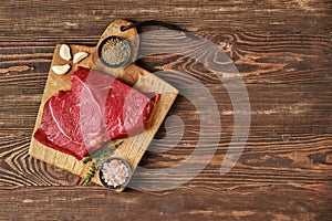 Overhead view of raw top side beef steak on wooden tabletop