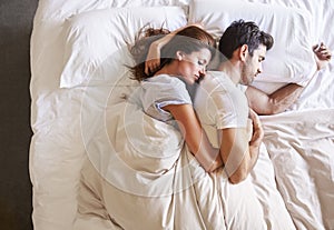 Overhead View Of Romantic Couple Lying In Bed Together