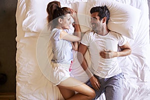 Overhead View Of Romantic Couple Lying In Bed Together