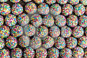 Overhead view of rows of small round cookies covered with colorful sprinkles