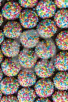 Overhead view of rows of small round cookies covered with colorful sprinkles