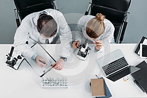 overhead view of scientific researchers in white coats working together at workplace