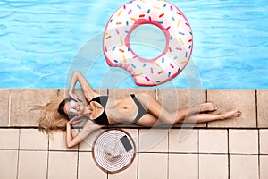 Overhead view of sexy young girl relaxing at poolside on summer day