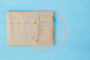 Overhead view of a single holiday package wrapped with eco friendly craft paper and tied with twine. Square format on a