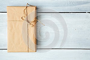 Overhead view of a single holiday package wrapped with eco friendly craft paper and tied with twine. Square format on a