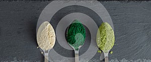 Overhead view on spoons with spirulina matcha and maca powders on stone board. Natural organic superfood supplements concept. Flat