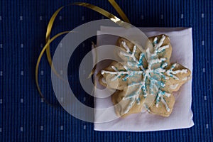 Overhead view of stack of snowflake shaped sugar cookies on white napkin with blue background