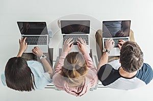 overhead view of students typing on laptops with blank screens