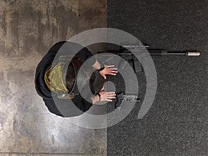 Overhead view of a tactical shooter training with a suppressed assault rifle and a handgun at a modern indoor range