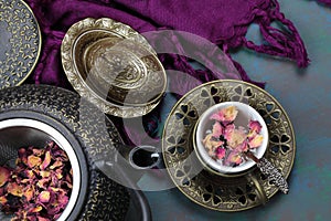 Overhead view of a tea cup of Rose tea with rose petals