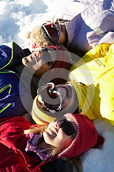 Overhead View Of Teenage Family Lying In Snow