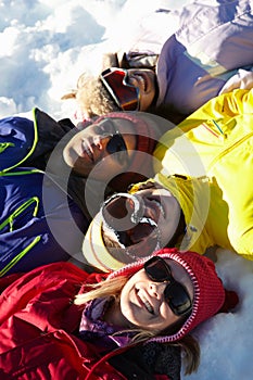 Overhead View Of Teenage Family Lying In Snow