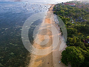 Overhead view of traditional boats moored off a tropical beach with fringing coral reef in Sanur