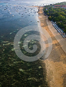 Overhead view of traditional boats moored off a tropical beach with fringing coral reef in Sanur