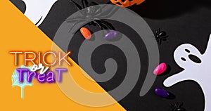 Overhead view of trick or treat text over spooky decorations and candies on black table