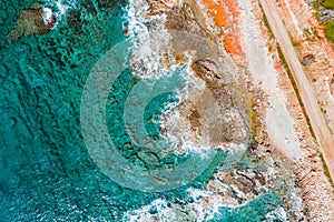 Overhead view of turquoise sea, waves and a rocky shoreline