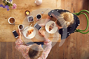 Overhead View Of Two Female Friends In Coffee Shop Meeting Up In Socially Distanced Way