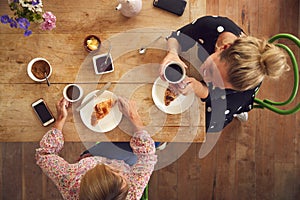 Overhead View Of Two Female Friends In Coffee Shop Meeting Up In Socially Distanced Way