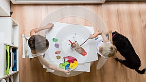 Overhead view of two toddler children painting with water colour