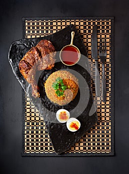 Overhead view of a West African entree of chicken, jollof rice and boiled egg